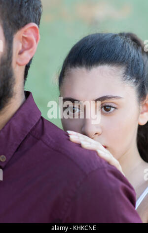 Junge Frau im Nahen Osten hinter ihrem Mann im Freien Stockfoto