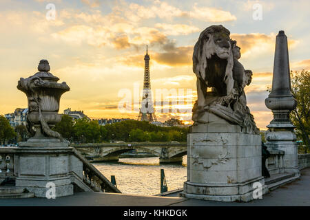 Der Eiffelturm bei Sonnenuntergang von der Brücke Alexander III mit einem Löwen Skulptur von Georges Gardet im Vordergrund gesehen. Stockfoto