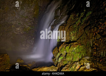 Schöne Nacht Blick auf den Wasserfall mit Hintergrundbeleuchtung in die Felsen und Steine, lange Belichtung Stockfoto
