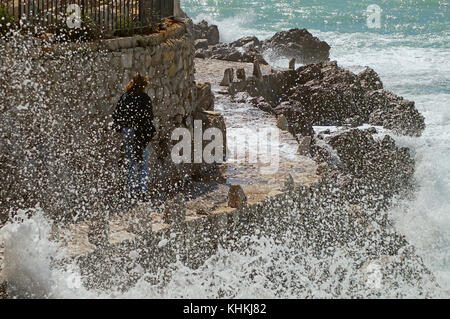 Frau gehen auf einen gefährlichen Weg an der Küste, während ein Sturm. Stockfoto