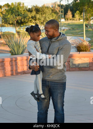 African American Dad Holding Tochter in einem Park. Stockfoto