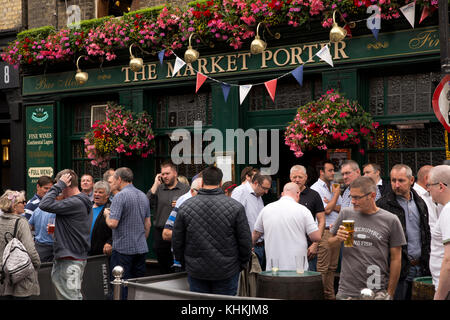 UK, London, Southwark, Stoney Street, Trinker unter Blumen hängende Körbe außerhalb Markt Porter pub Stockfoto