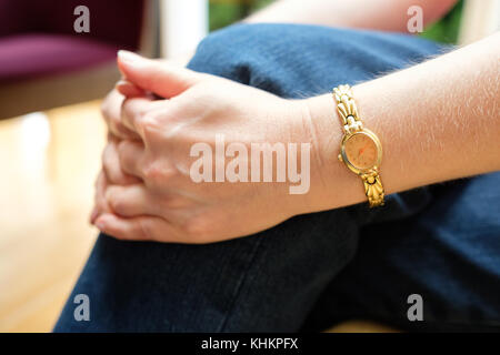 Gefalteten Händen und Arm mit goldenen watch Holding einen Fuß Stockfoto