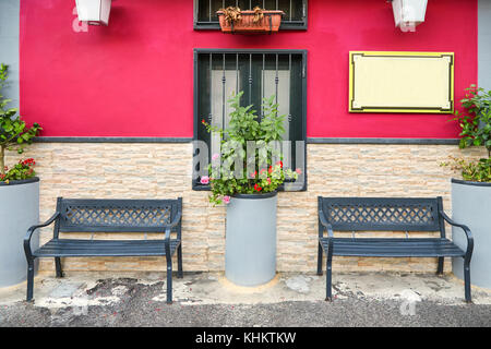 Zwei leere Bänke in der Nähe der schönen Fassade eines Cafe in rosa malte auf einer der italienischen Straßen Stockfoto