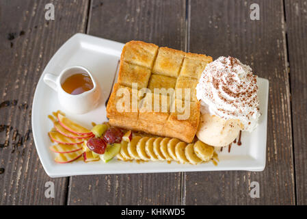 Honig Toast mit Vanilleeis, Trauben, Kiwi, Banane, Apfel und Sahne Stockfoto