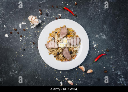 Pilav auf Platte mit orientalischen Ornament auf einem dunklen Hintergrund. zentral-asiatische Küche - Plov. Ansicht von oben. Stockfoto