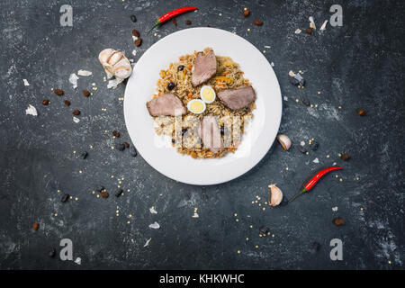 Pilav auf Platte mit orientalischen Ornament auf einem dunklen Hintergrund. zentral-asiatische Küche - Plov. Ansicht von oben. Stockfoto