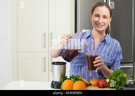 Porträt der Frau, Saft oder Smoothie in der Küche Stockfoto