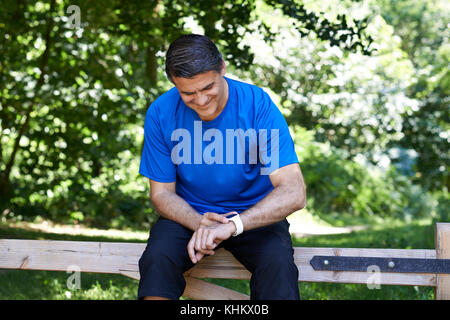 Reifen Mann an Activity Tracker beim Training in der Landschaft suchen Stockfoto