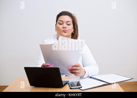 Junge weibliche spanischer Arzt hinter dem Schreibtisch beim Vergleich der Daten auf den Unterlagen Stockfoto