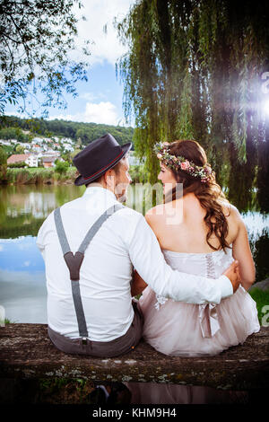 Foto von einem jungen Paar, das bald zu heiraten, sitzen auf einer Bank am See und die schöne Landschaft. Stockfoto