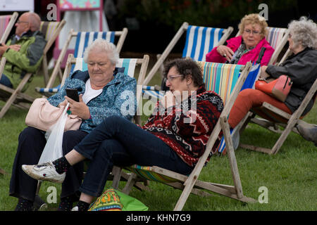 Bei kaltem Wetter, Leute sitzen, ruhen & Chat in Liegestühlen auf den ersten RHS Flower Show-Chatsworth Chatsworth House, Derbyshire, England, UK. Stockfoto