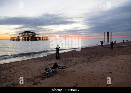 Brighton, UK. Ein Fahrrad ist auf den Boden gefallen wie seine Besitzer aus zu fotografieren, eine spektakuläre Starling murmuration über Brighton's aufgegebenen West nimmt Stockfoto