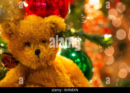 Brauner Teddybär in close-up gegen die bunten glitzernden chirstmas ball Verzierungen auf den glitzernden burrly Hintergrund der Lichter Effekt von behi Stockfoto