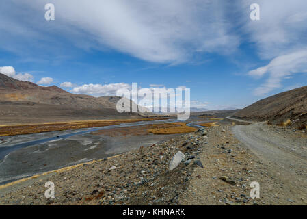 Die malerischen Steppe Landschaft mit Bergen, gewundenen Fluss, steinigen Weg entlang des Flusses und im Herbst die Vegetation auf dem Hintergrund des blauen Himmels und b Stockfoto