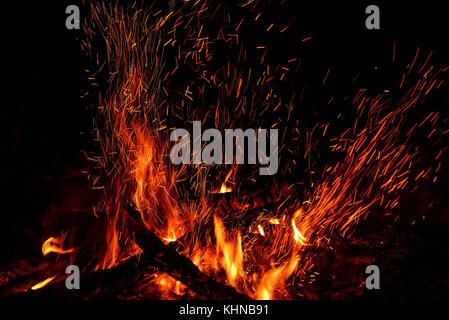 Rot und Orange Flammen der Scheiterhaufen und Funken in Form von Tracks auf schwarzem Hintergrund Stockfoto