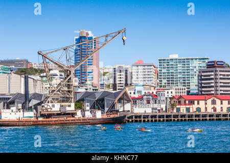 Wellington Waterfront, mit dem Schwimmkran raukura hikitia, te und die boatshed, und Leute Kajakfahren in den Hafen. Stockfoto