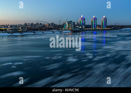 Den malerischen Blick auf die Stadt und den Fluss mit den Überlegungen der Lichter im Wasser und Eis, Schuß auf eine lange Belichtung Stockfoto