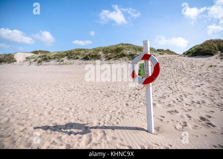 Lebensretter hängen an einen Post auf einer skandinavischen Strand in roten und weißen Farben im Sommer Stockfoto