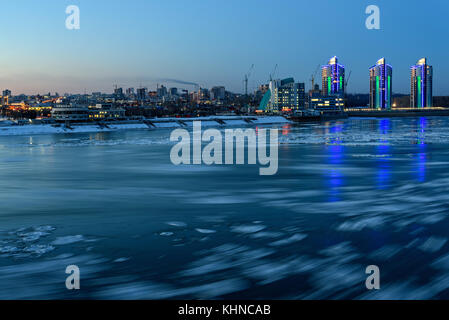 Den malerischen Blick auf die Stadt und den Fluss mit den Überlegungen der Lichter im Wasser und Eis, Schuß auf eine lange Belichtung Stockfoto