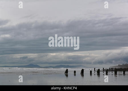 Blick Meer auf den Lynn Halbinsel von tywyn Strand mit buhnen am Strand im Vordergrund. Stockfoto