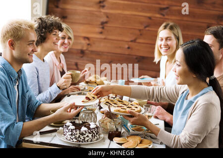 Eine junge Frau, die dem lächelnden Kerl beim Weihnachtsessen das letzte Stück Kuchen gibt Stockfoto
