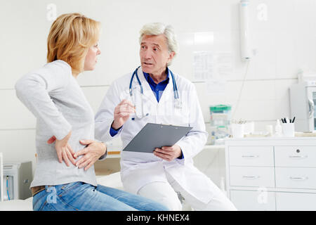 Reifer Arzt gibt Empfehlungen für seinen Patienten mit Schmerzen in der rechten Flanke Stockfoto
