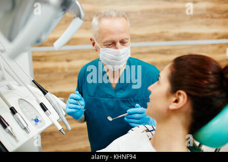 Reifen Zahnarzt in Uniform an seinen Patienten suchen, während sie ihre Beschwerden Stockfoto