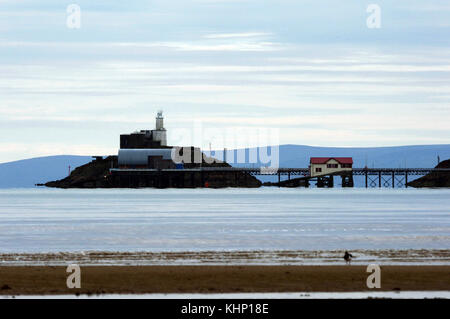 Mumbles Rettungsboot Station, Mole und Leuchtturm mit Devon im Hintergrund. Mumbles war der beste Ort in Wales 2018 zu Leben gestimmt. Stockfoto