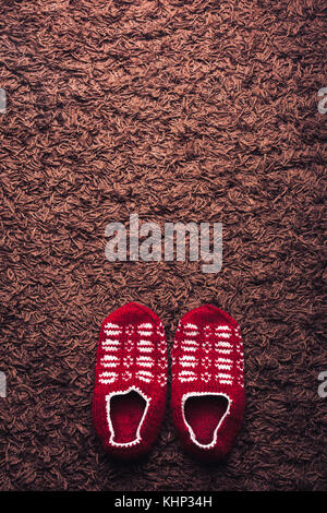Füße tragen rot gemusterten Socken auf braunen Teppich Hintergrund. Komfort Konzept. Stockfoto
