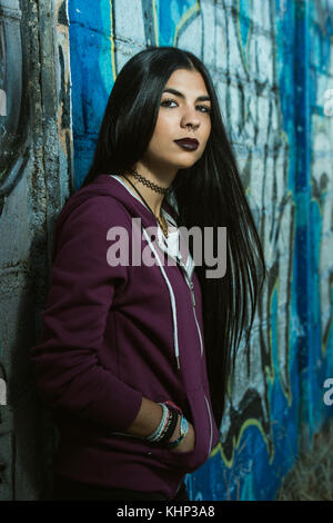 Ein grunge gestaltet und dunkelhaarige Frau mit einem violetten Sweatshirt mit Kapuze Stockfoto