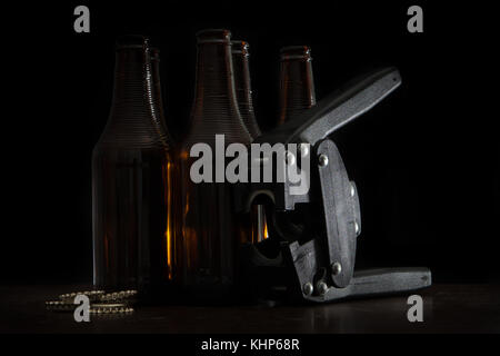 Die ganze Länge der Hand capper mit fünf dunkle braune Flaschen und Verschlüsse und über schwarzen Hintergrund Stockfoto