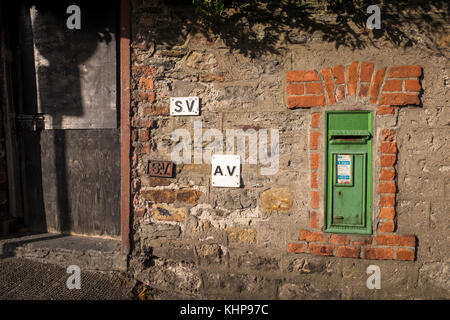 Grüne Post Box für den Versand von Briefen, in einem roten Backsteingebäude aus dem Rahmen in einer Mauer aus Stein mit SV und AV-metall Plaketten, Waterford, Irland Stockfoto