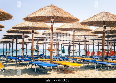 Leere Sunchair Liegestühle am Strand unter Sonnenschirmen, mit Blick auf das blaue Meer in Paralia Katerini Stockfoto