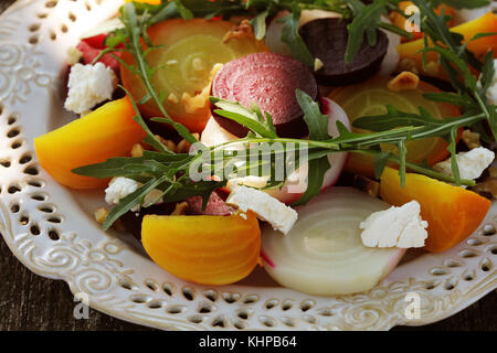 Gesunde Rüben Salat mit roten, weißen und goldenen Rüben, Rucola, Muttern, Feta Käse auf Holz- Hintergrund Stockfoto