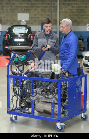 Schüler mit Lehrer, die Reparatur eines Autos während der Lehrzeit Stockfoto