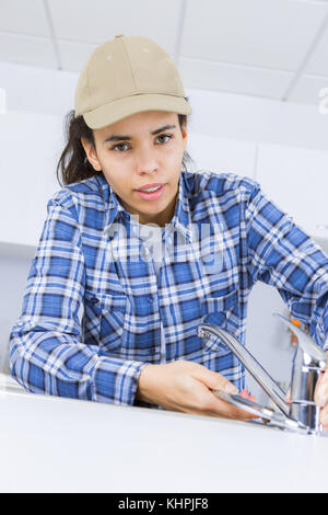 Weibliche Klempner Arbeiten am Waschbecken mit einem Schraubenschlüssel Stockfoto