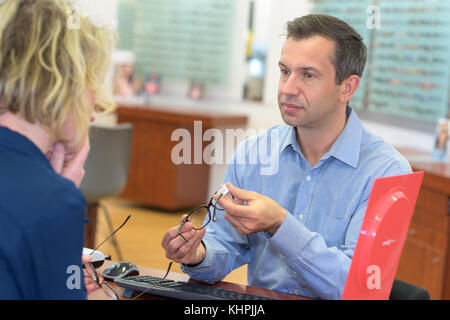 Ernsthafte Frau Vergleich der beiden Brillen Stockfoto
