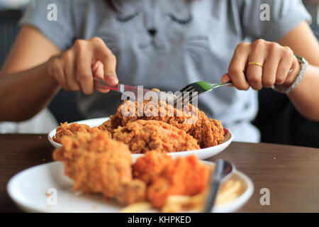 Junge Frau schneiden Fried Chicken wählen Sie Fokus, gebratenes Huhn Mittagessen, close-up Frau Hände schneiden Fried Chicken, essen gebratenes Huhn mit Freundin, se Stockfoto