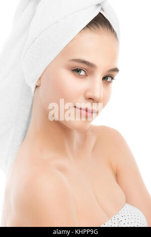 Schöne junge brünette Frau mit sauberem Gesicht und ein Handtuch auf dem Kopf. isoliert.
