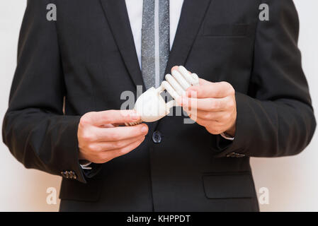 Ein Mann im Anzug hält eine Energiesparlampe Stockfoto