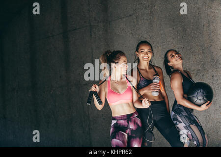 Glückliche junge Frauen gemeinsam und lächelnd nach dem Training. Gruppe von weiblichen Freunden entspannen nach Training im Freien. Stockfoto
