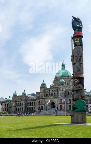 Totem Pole mit British Columbia Parlament im Hintergrund - Victoria, Kanada. Stockfoto