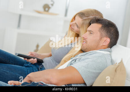 Seitenansicht des Paares auf der Couch vor dem Fernseher Stockfoto
