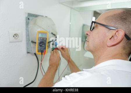 Messung von Spannung in der Steckdose mit einem Multimeter Stockfoto