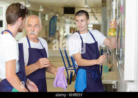 Junge männliche Arbeiter mit der Reinigung der Geräte Boden wischen Stockfoto