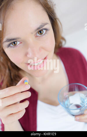 Glückliche junge Frau, die die Pille Stockfoto