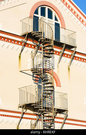 Spirale Feuertreppe außerhalb eines Gebäudes. Balkonen auf jeder Etage. Stockfoto