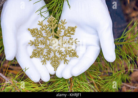 Hände in Handschuhe halten künstliche Schneeflocke Stockfoto