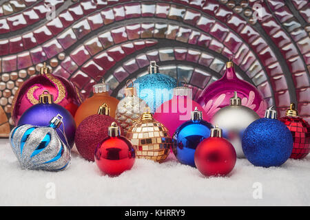 Viele schöne dekorative Weihnachtskugeln auf Schnee Stockfoto